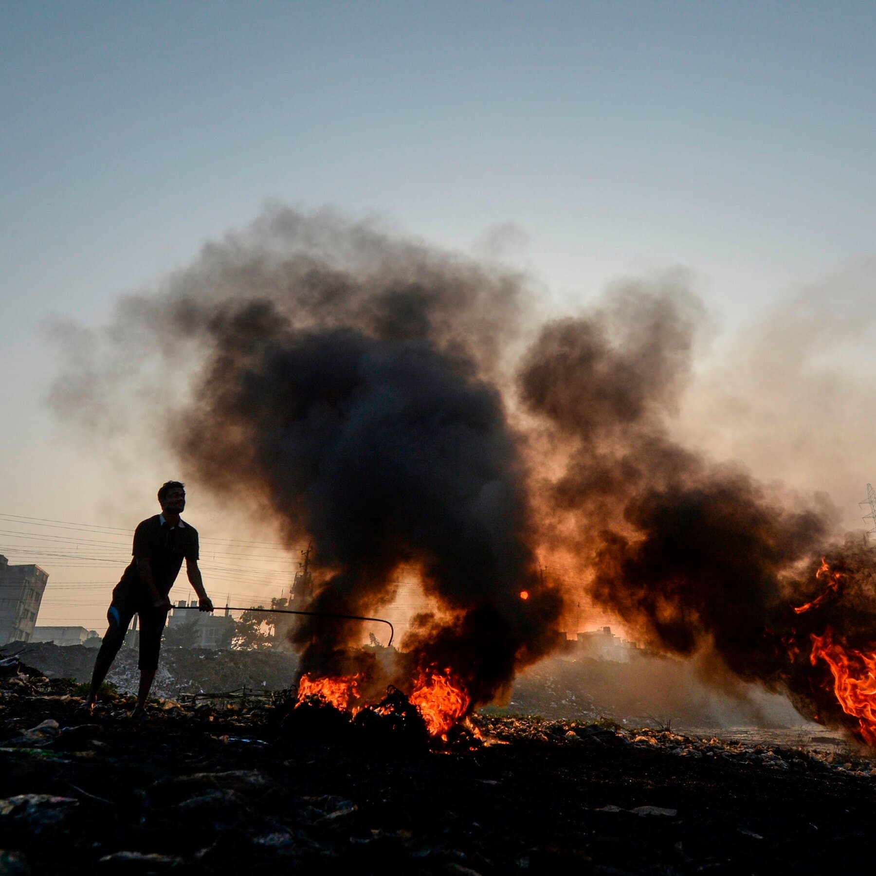 Person standing beside burning agricultural waste